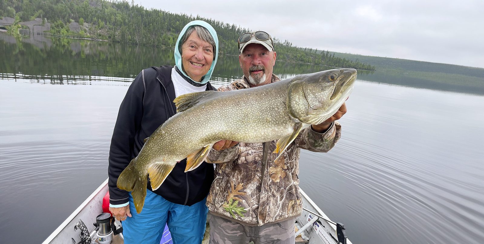 Anglers holding a lake trout aboard a boat on Russell Lake, Saskatchewan