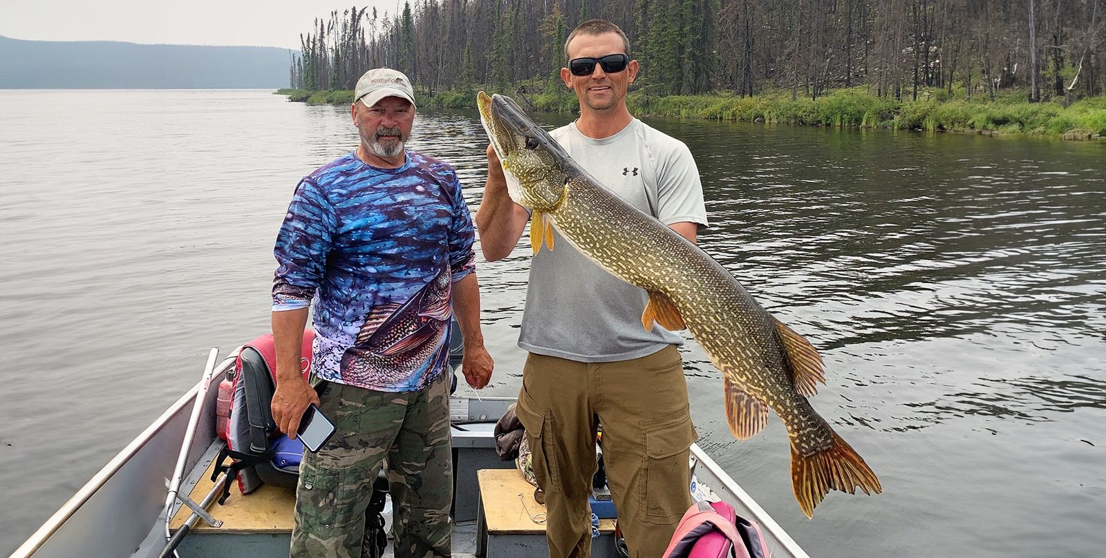 Two anglers holding a large northern pike in a boat on Russell Lake
