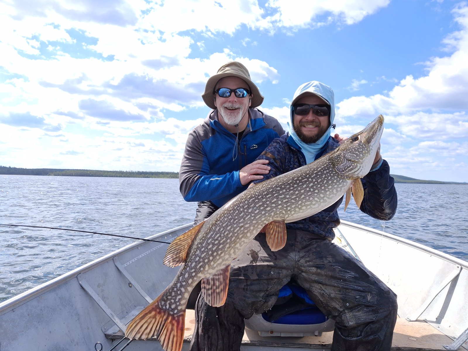 Two anglers holding a large northern pike in a boat on Russell Lake, Saskatchewan