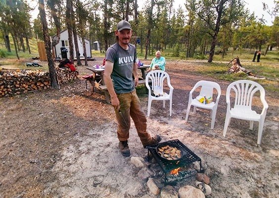 A guest cooking over an open fire at the Wheeler River Outcamp